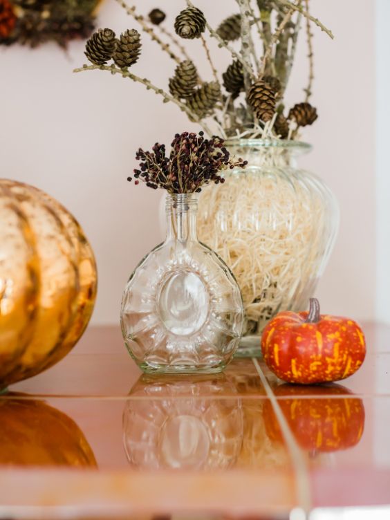 objets décoratifs naturels avec un vase contenant des branches de pins avec des pommes de pin, des fleurs séchés et une mini citrouille / visiondeco